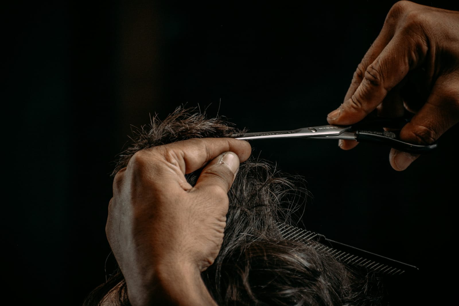 Mains coupant des cheveux avec des ciseaux en acier